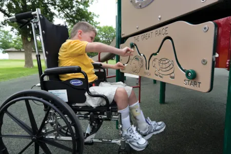 Young boy in wheelchair playing with The Great Race playground game panel